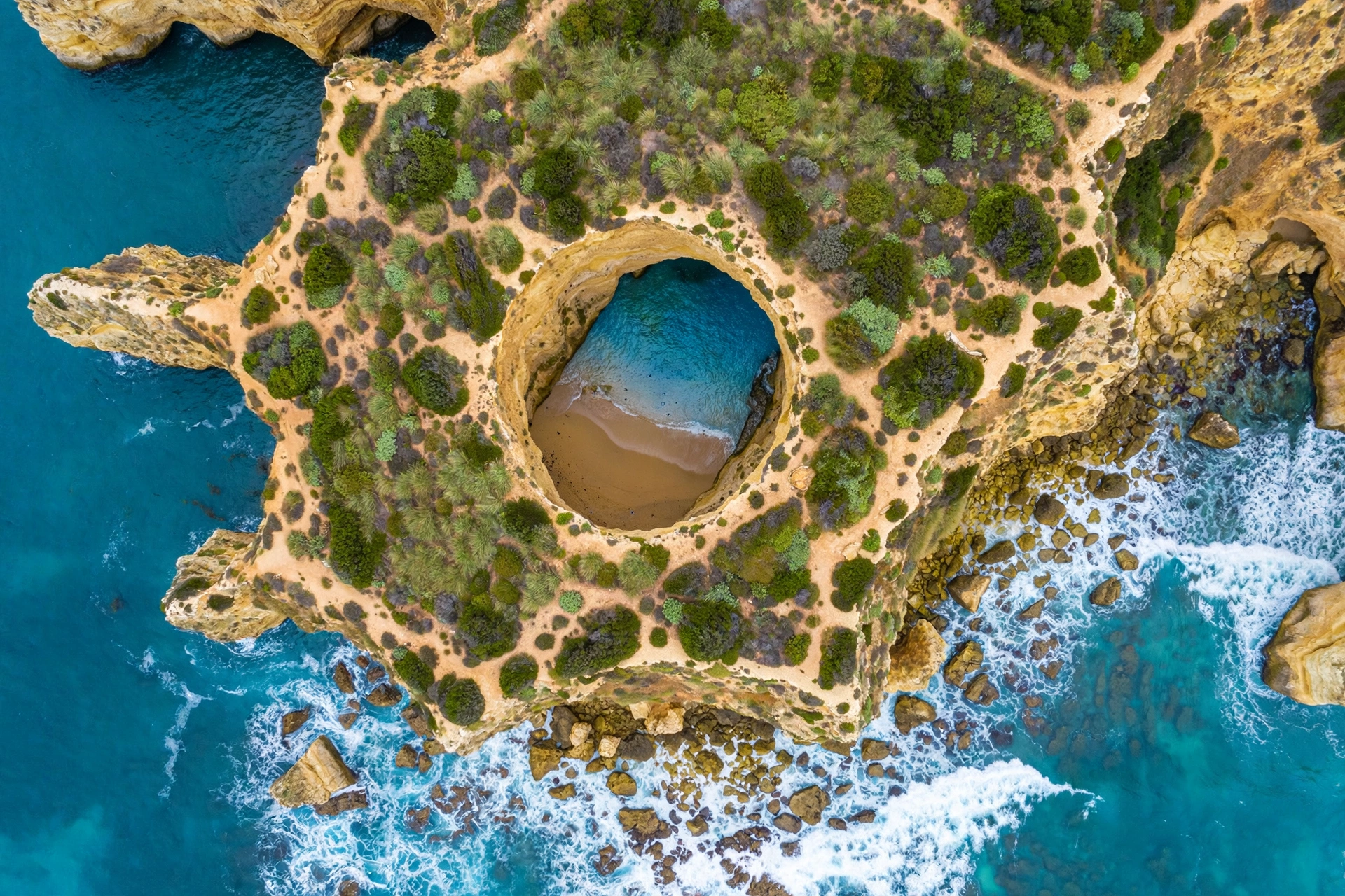 Aerial drone view of the circular skylight opening in the Benagil clifftop from above