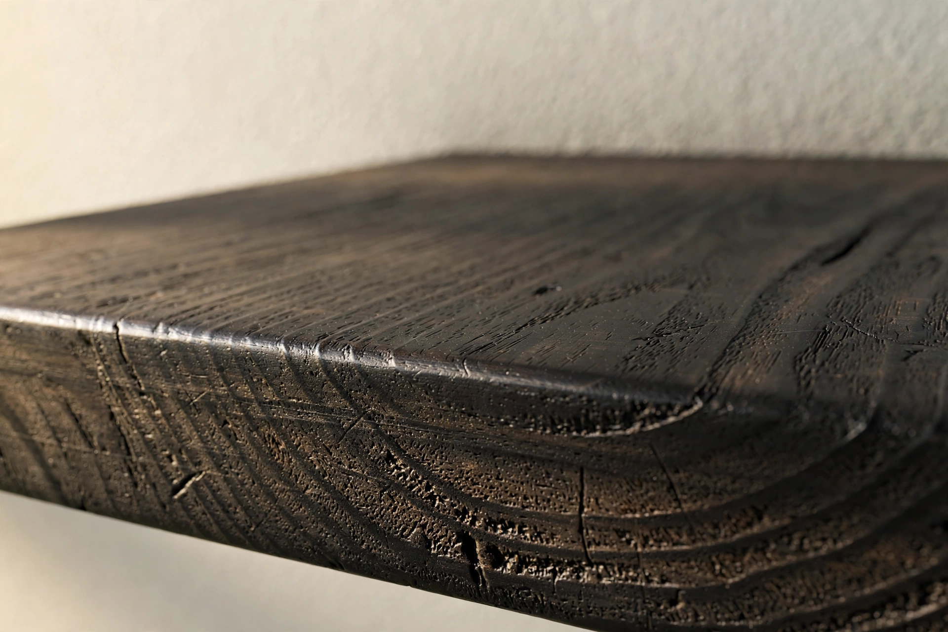 Close-up of black stained solid wood floating shelf edge showing natural grain
