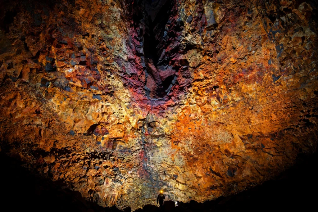 Mineral-streaked red and gold rock walls inside Thrihnukagigur's magma chamber, Iceland