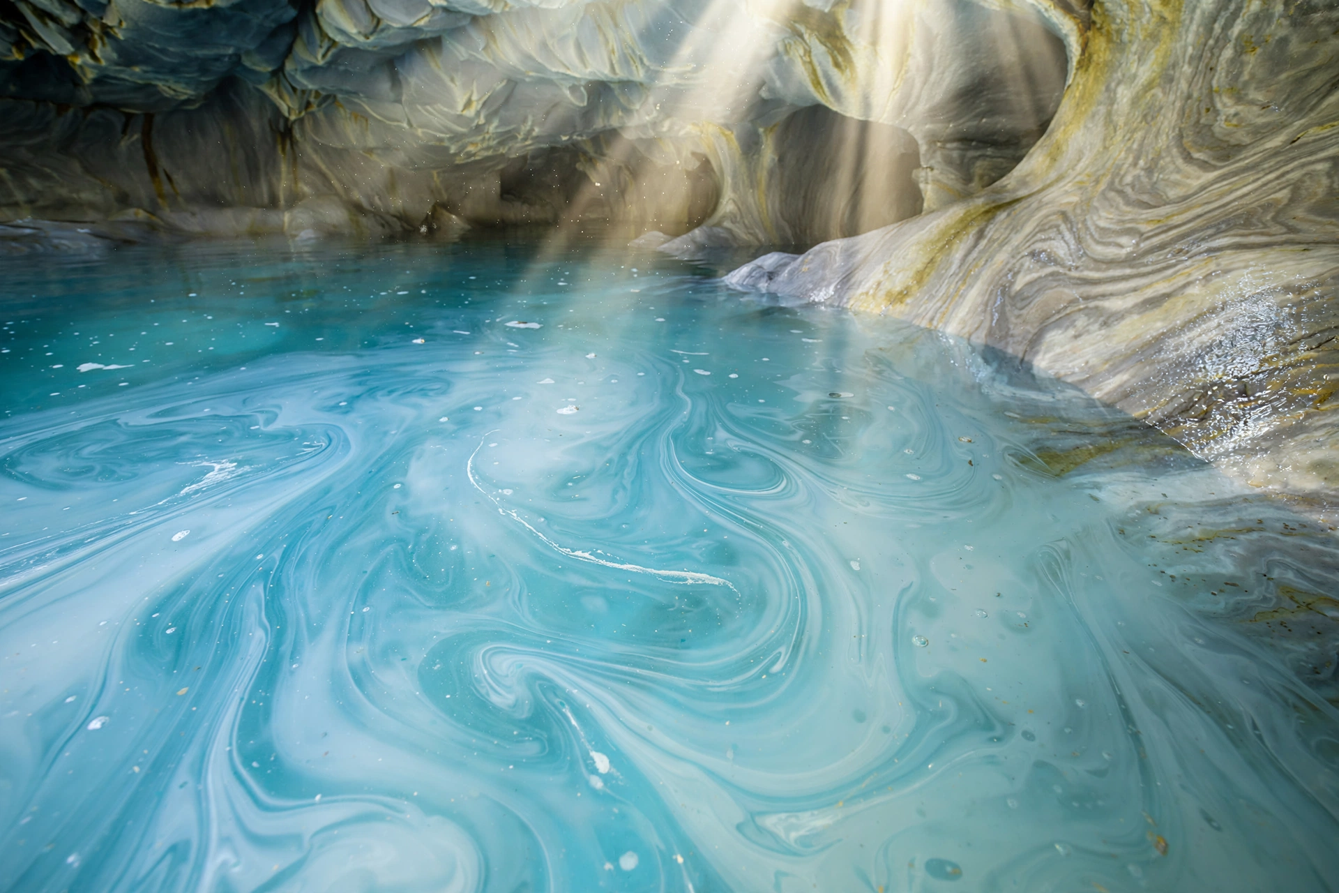 Glacial turquoise water with rock flour creating milky blue gradients inside Chile's Marble Caves